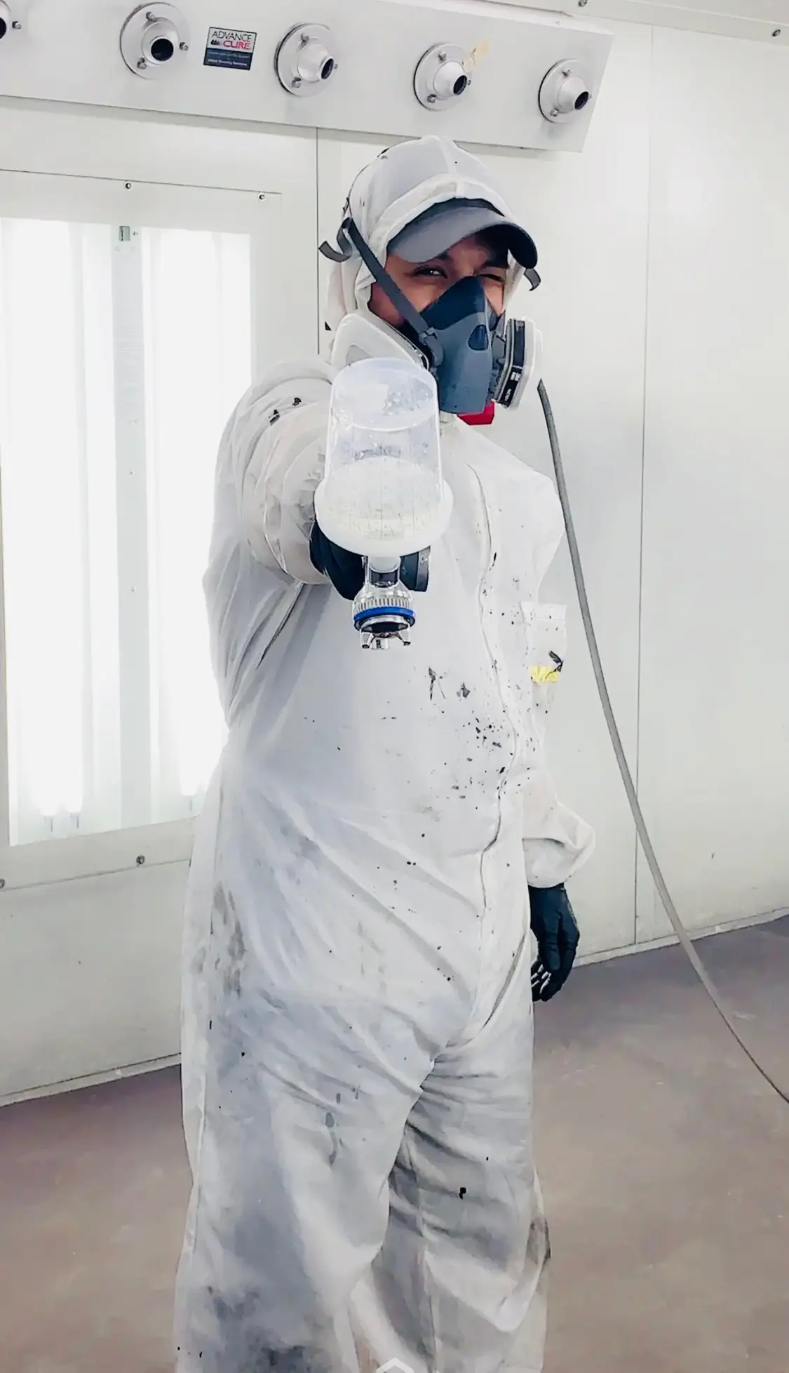 Jonathan Crespo in the spray booth, gun in hand.