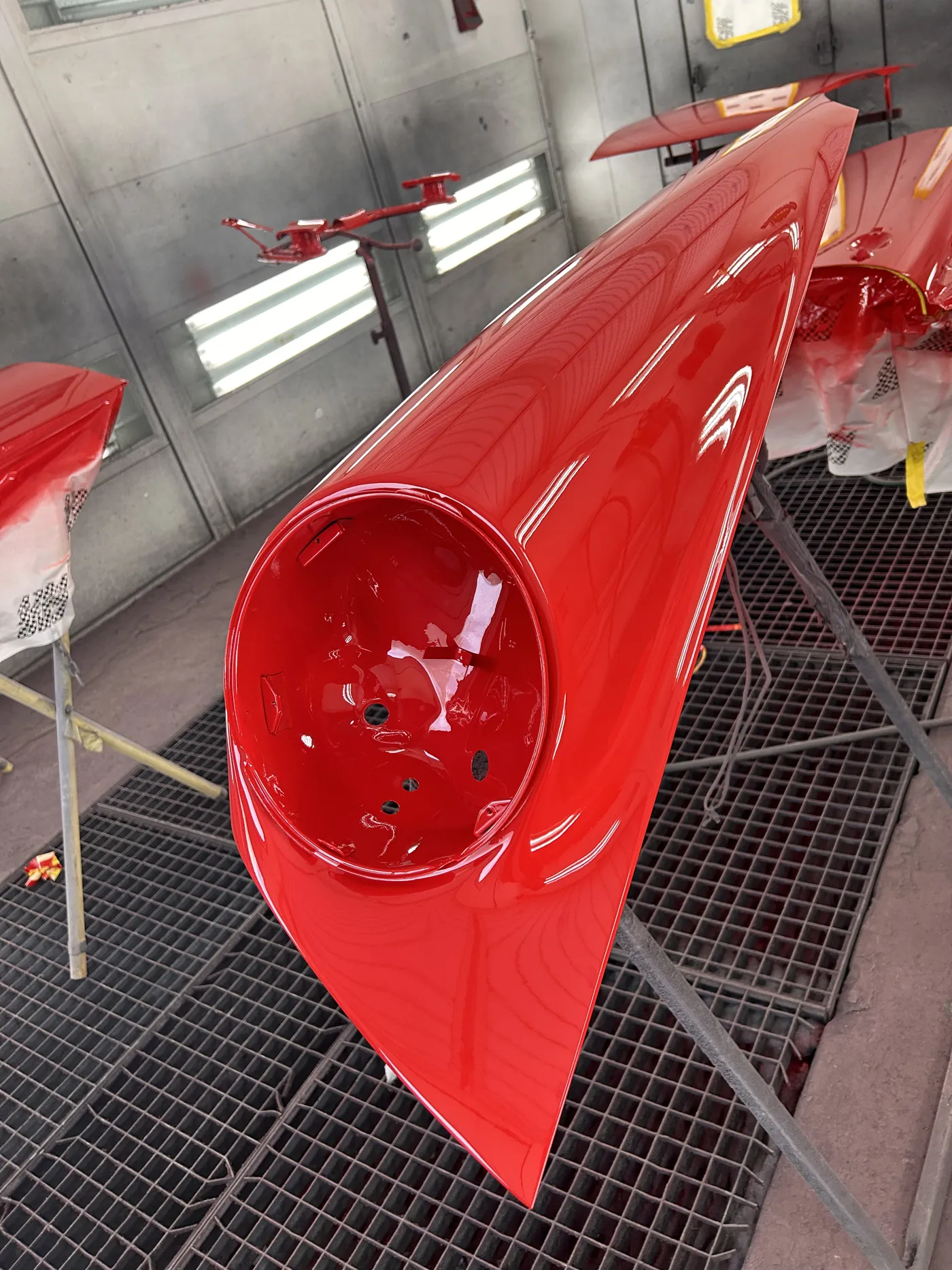 Freshly painted glossy red Porsche 911 fender drying in the spray booth.