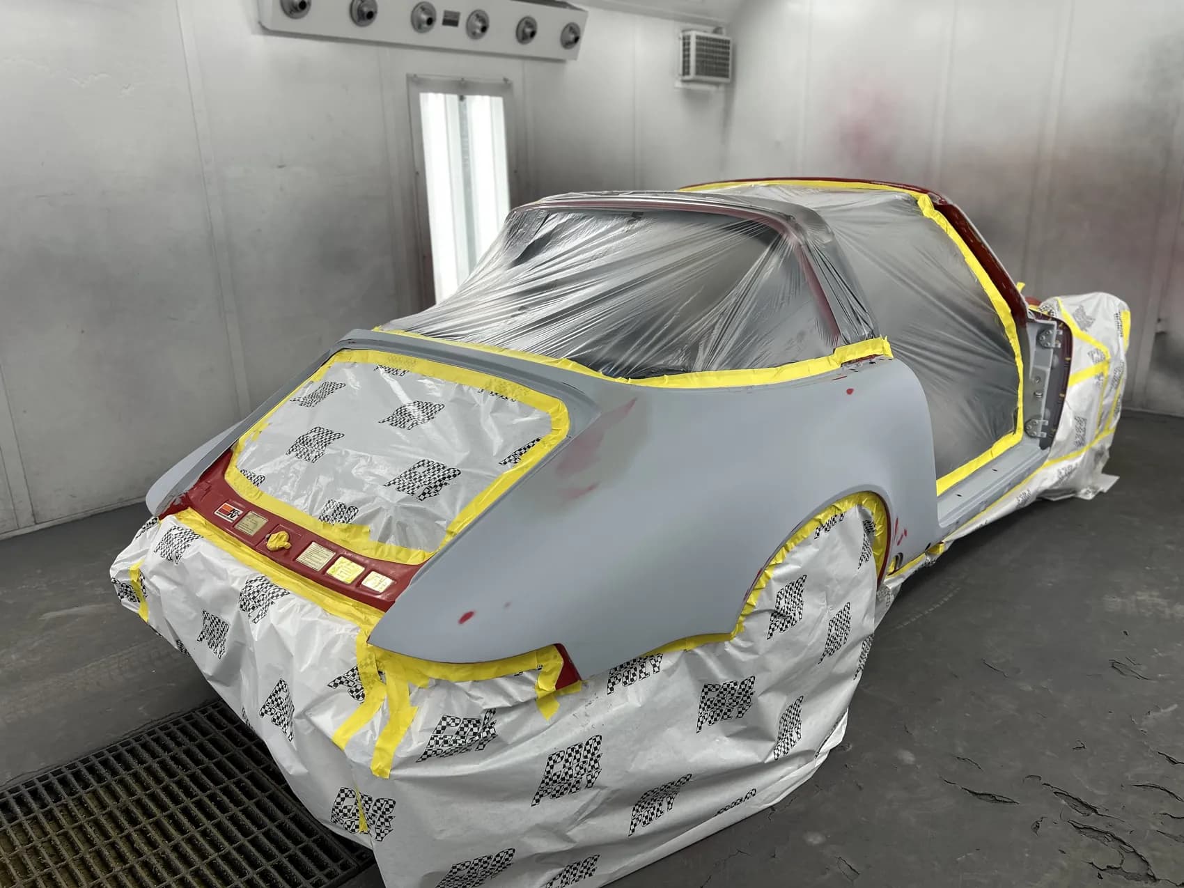 Classic Porsche 911 in grey primer, masked in the spray booth.